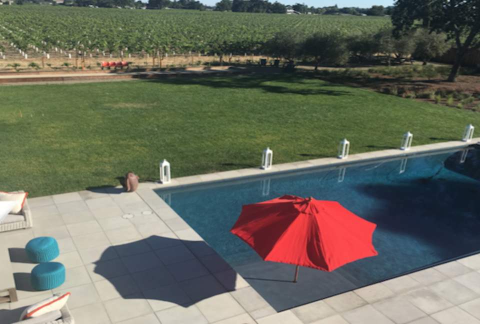 The view of the pool, lawn, bocce ball court and vineyards