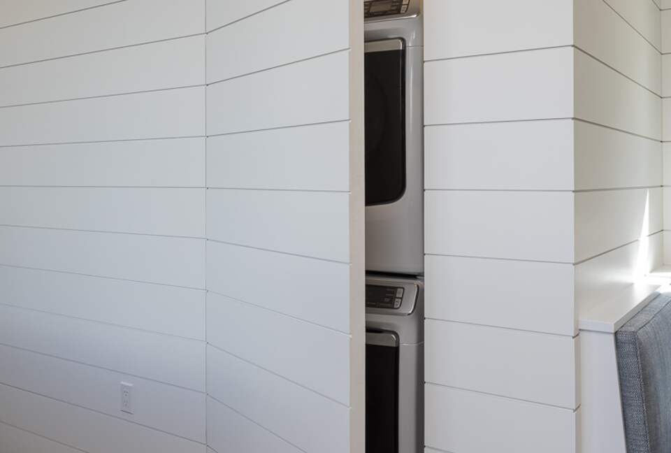 Stacked washer & dryer hidden behind shiplap wall doors.