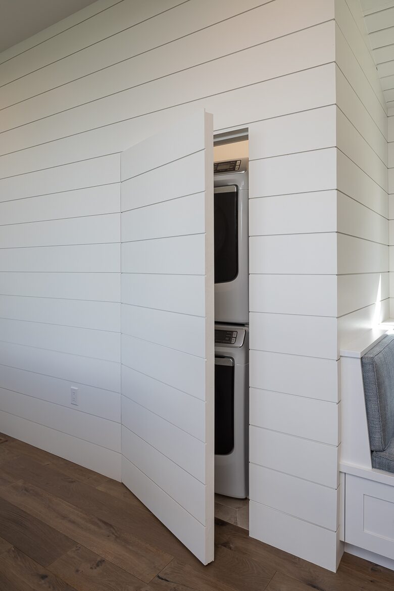 Stacked washer & dryer hidden behind shiplap wall doors.