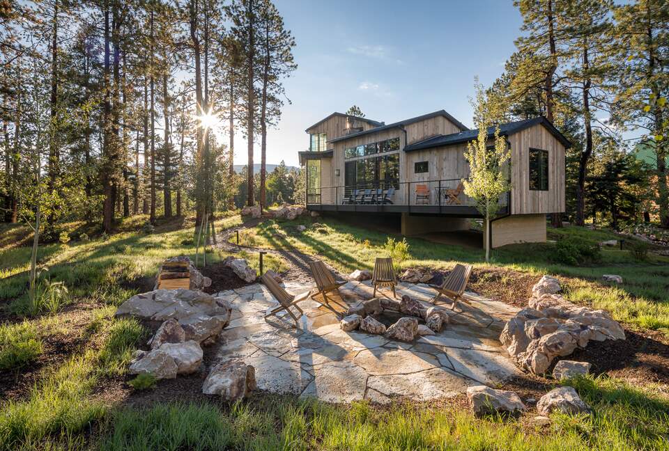 Stone fire pit with seating and the house in the distance.