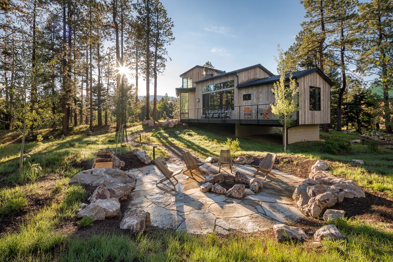 Stone fire pit with seating and the house in the distance.