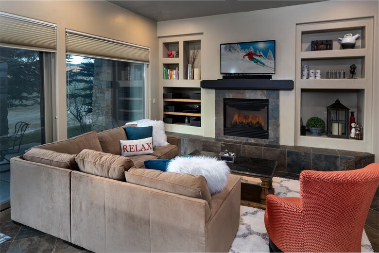 Living room with fireplace, tan sectional, and red arm chair