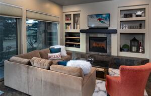 Living room with fireplace, tan sectional, and red arm chair