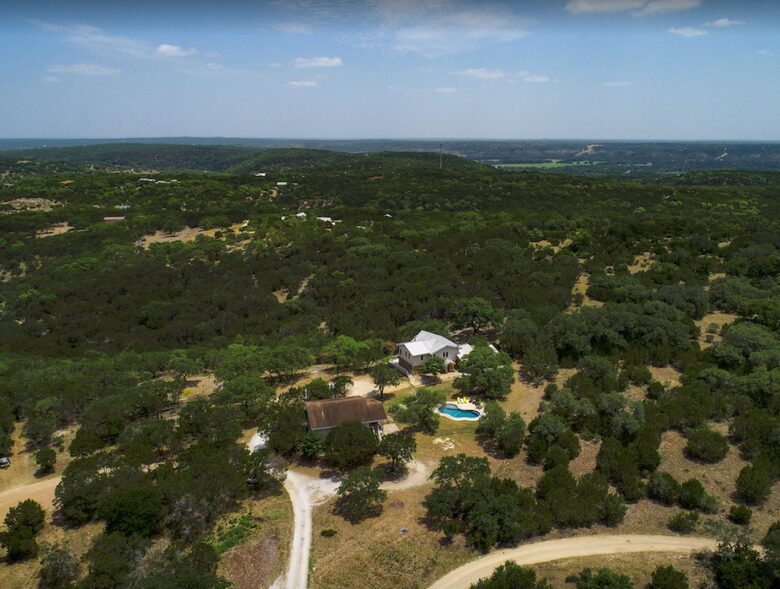 Aerial view of property, pool, and tree landscape