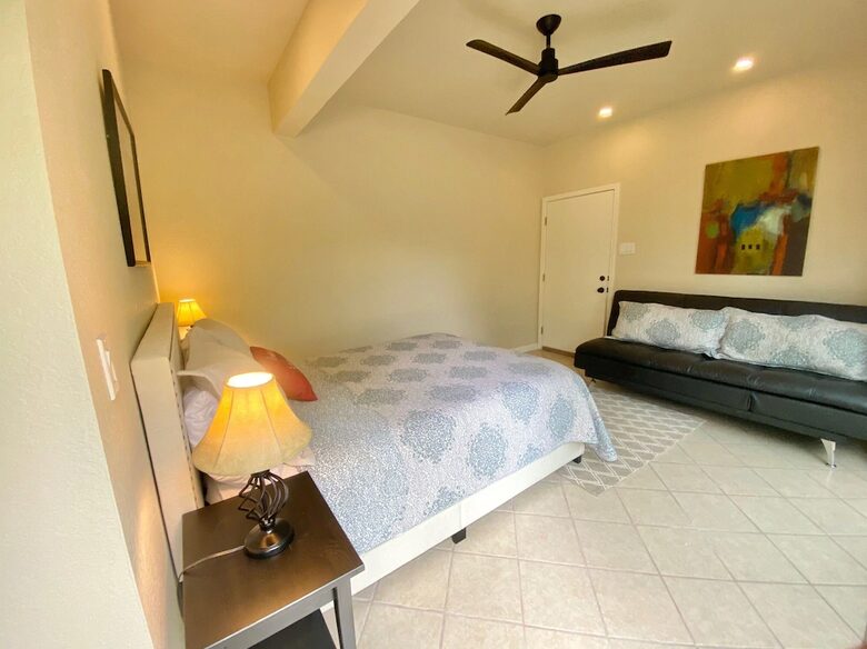 Downstairs master queen bed and dark grey futon couch