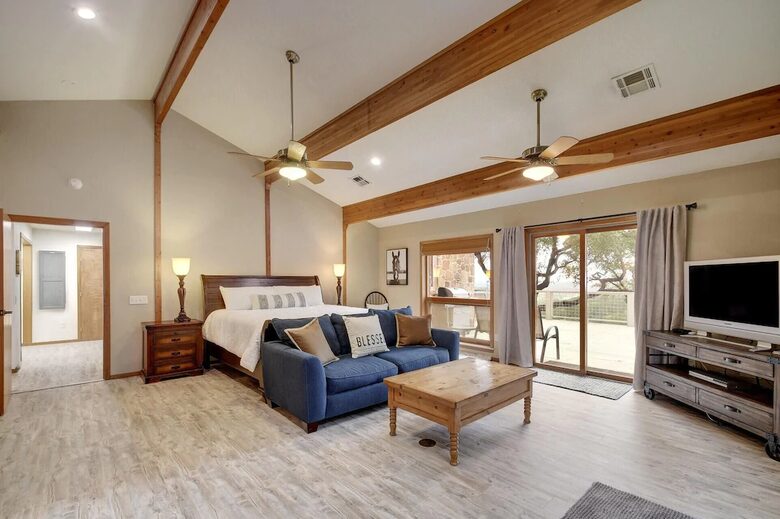 Downstairs master bedroom with king bed, blue sofa, and TV