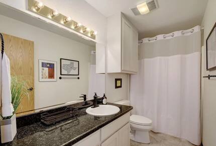 Full guest bathroom with dark granite countertops