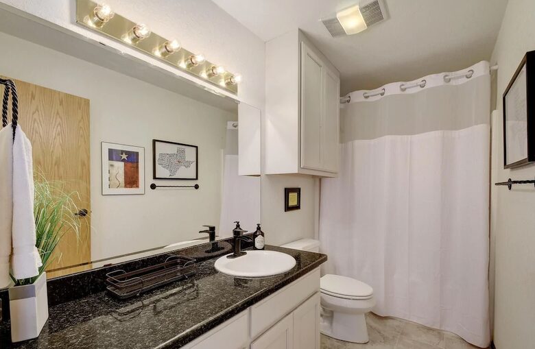 Full guest bathroom with dark granite countertops