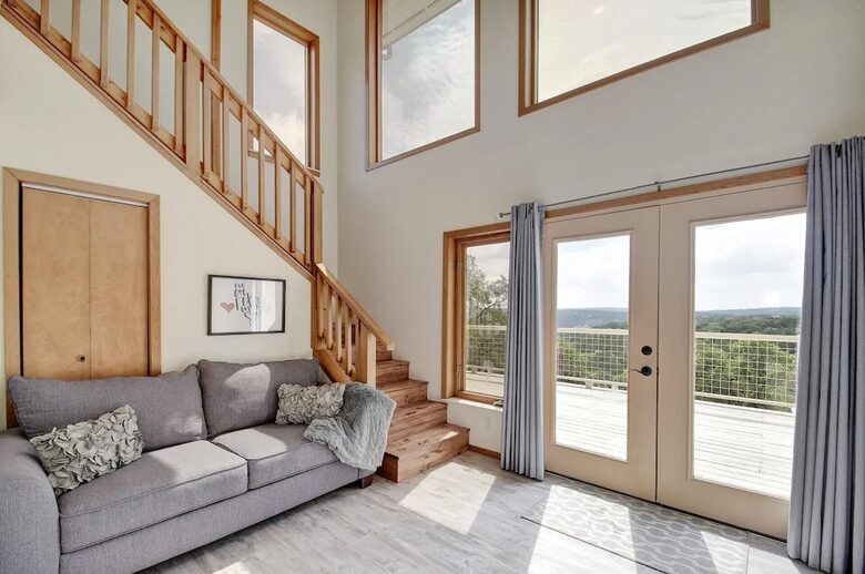 Full grey sleeper sofa, stairs, and french doors