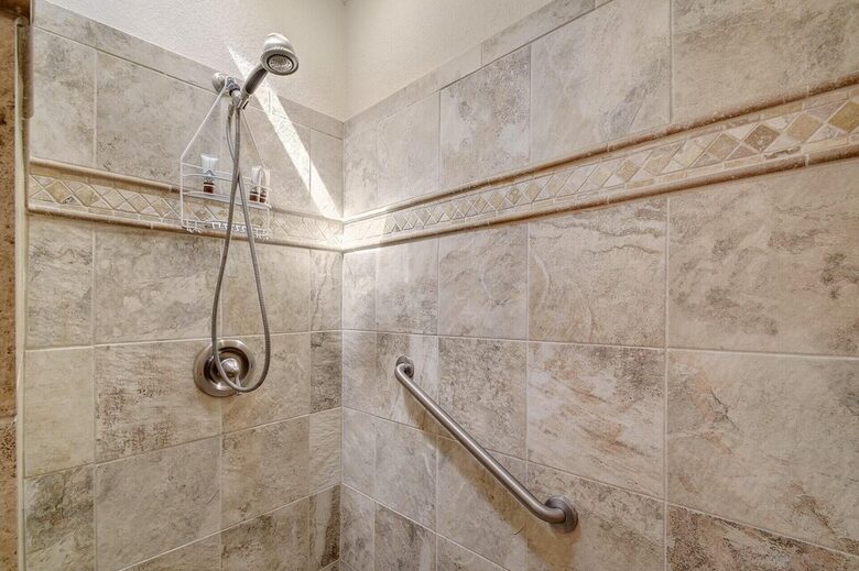 Downstairs master tiled shower with hand rail & shower head