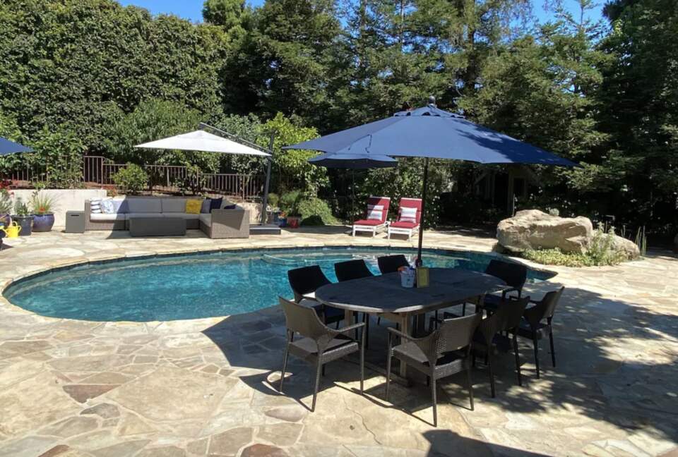 Backyard pool with plenty of seating and umbrellas