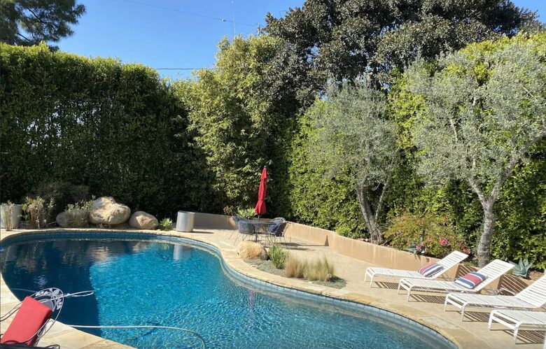 Heated pool with multiple lounge areas and umbrellas