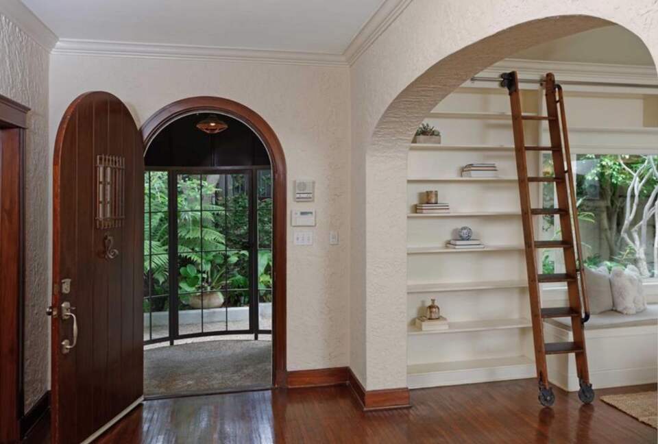 Arched entryway with hardwood floors and library ladder