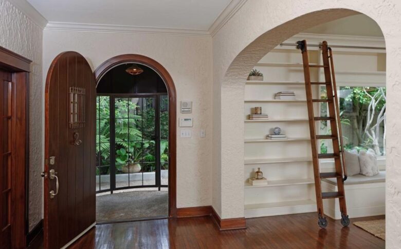 Arched entryway with hardwood floors and library ladder