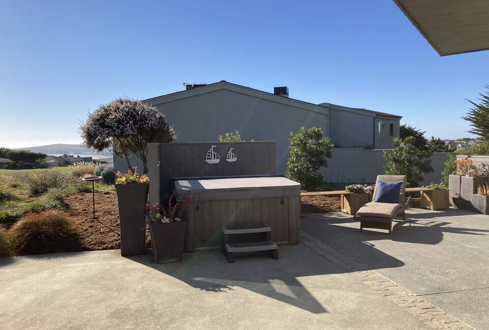 Hot tub and sun lounger at side patio.