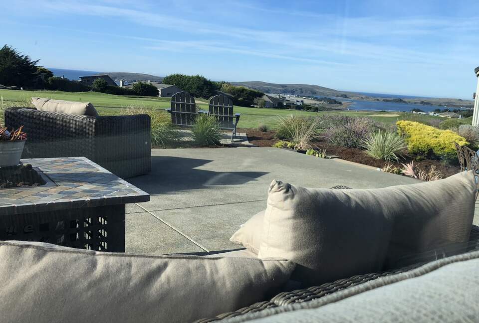 Looking outside from sofa to patio with lounge and firepit.