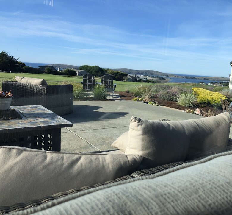 Looking outside from sofa to patio with lounge and firepit.
