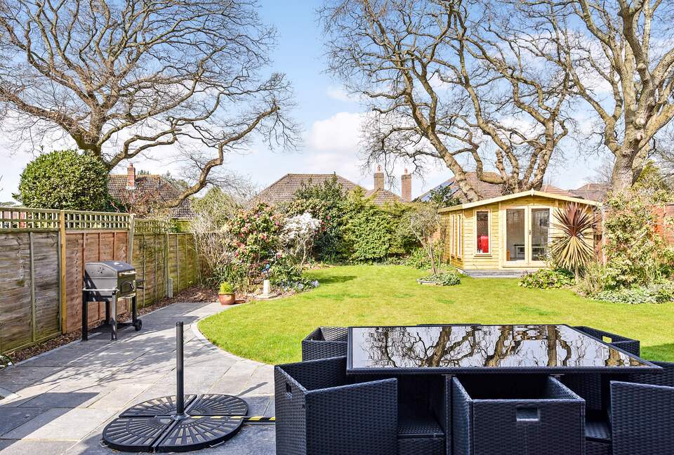 Rear garden. Large patio. Table, chairs and charcoal BBQ.