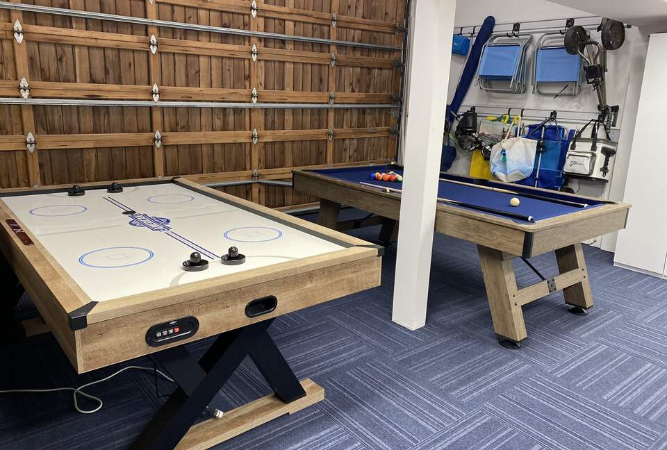 Gaming area adjacent to sports/beach accessories in garage.