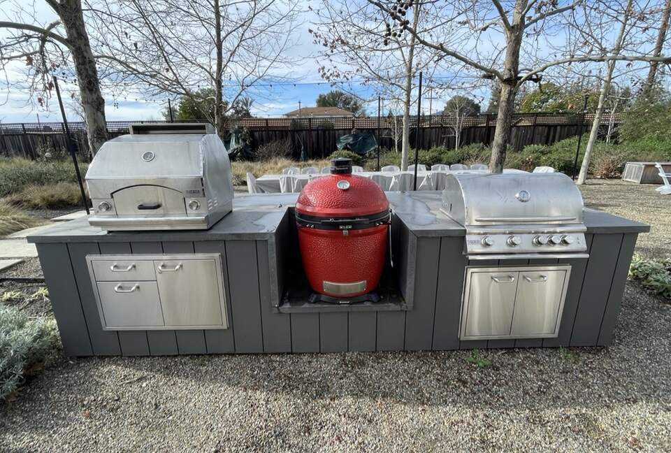 The BBQ area with pizza oven, Kamado Joe, and gas grill.