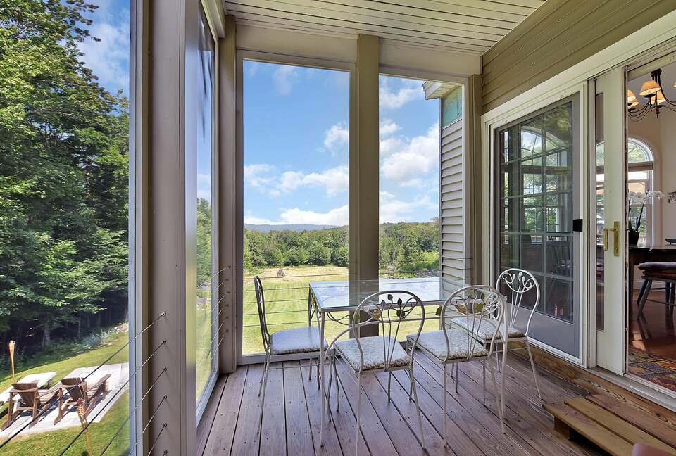 SCREENED IN SIDE PORCH WITH TABLE, CHAIRS AND TWO LOUNGE CHAIRS.