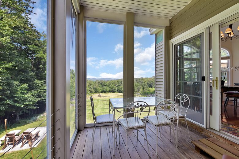 SCREENED IN SIDE PORCH WITH TABLE, CHAIRS AND TWO LOUNGE CHAIRS.
