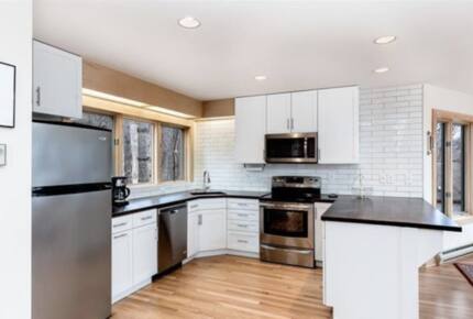Renovated electric kitchen and bar-top seating for three.